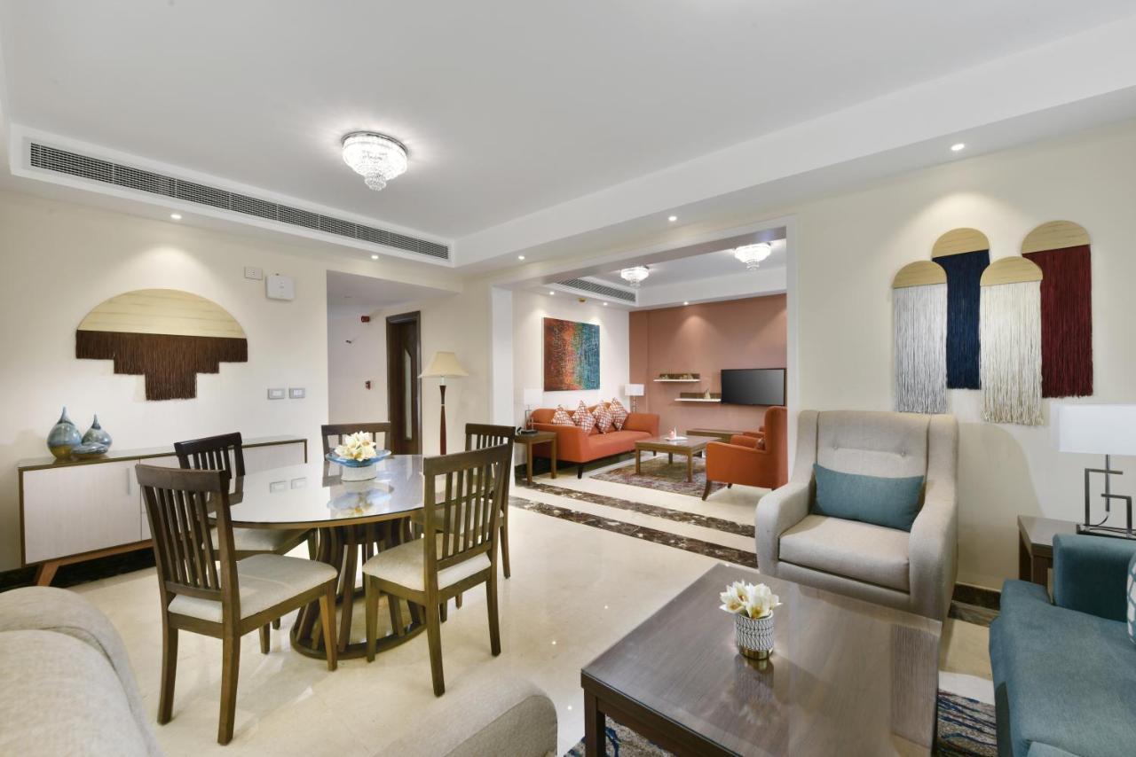 Tolip Resort El Galala Majestic Ain Sukhna Exterior photo The photo shows a modern living room space that is elegantly designed. It features a seating area with a comfortable sofa and armchairs, complemented by a decorative coffee table. There is a dining table with several wooden chairs, providing a cozy a