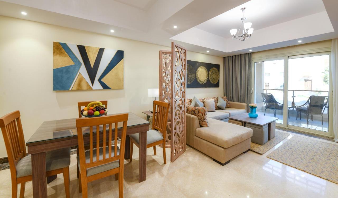 Tolip Resort El Galala Majestic Ain Sukhna Exterior photo The photo shows a modern and stylish interior of a living space. It features a seating area with a plush sofa and decorative cushions, complemented by a wooden coffee table. There is a dining table with wooden chairs nearby. 

On the walls, there are