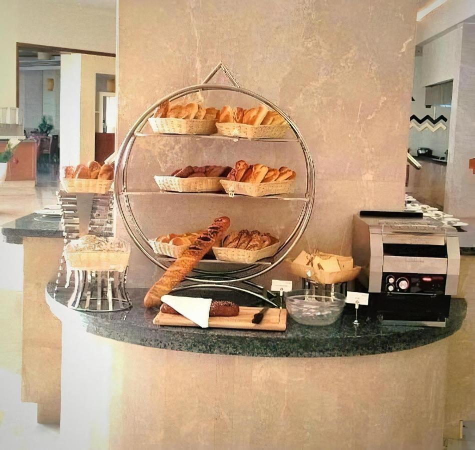 Tolip Resort El Galala Majestic Ain Sukhna Exterior photo The photo shows a display of various types of bread and pastries arranged on a countertop. There are several baskets stacked on a circular stand, filled with different baked goods like croissants and rolls. A long baguette is placed horizontally on a